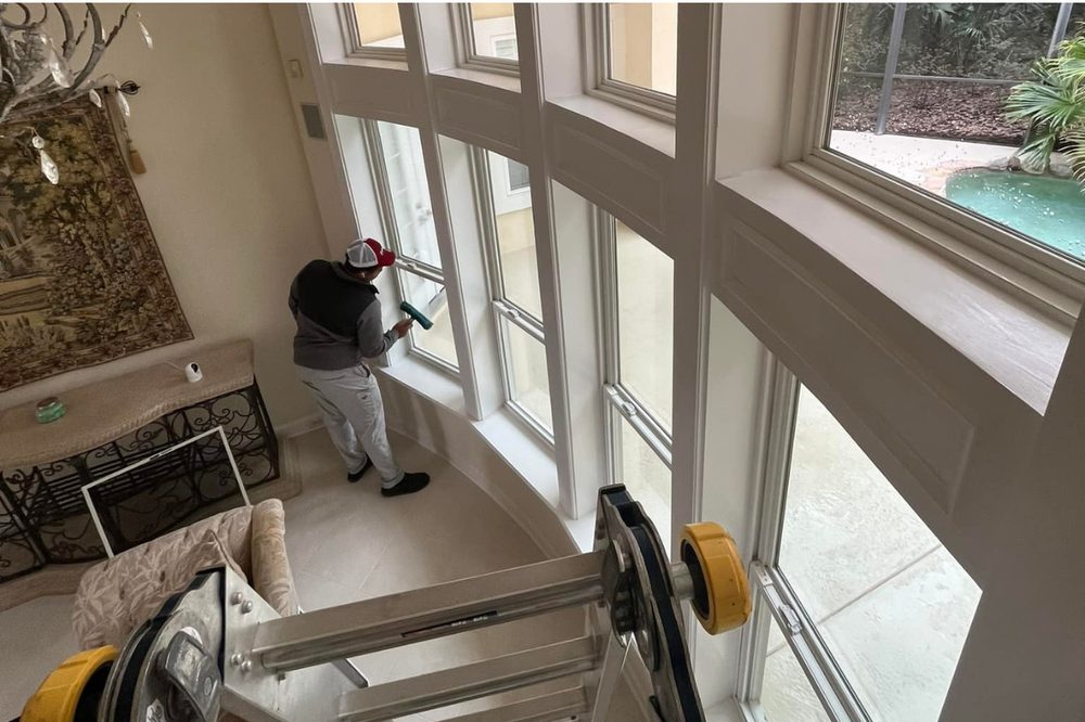 Window Washing Warriors technician cleaning tall interior windows